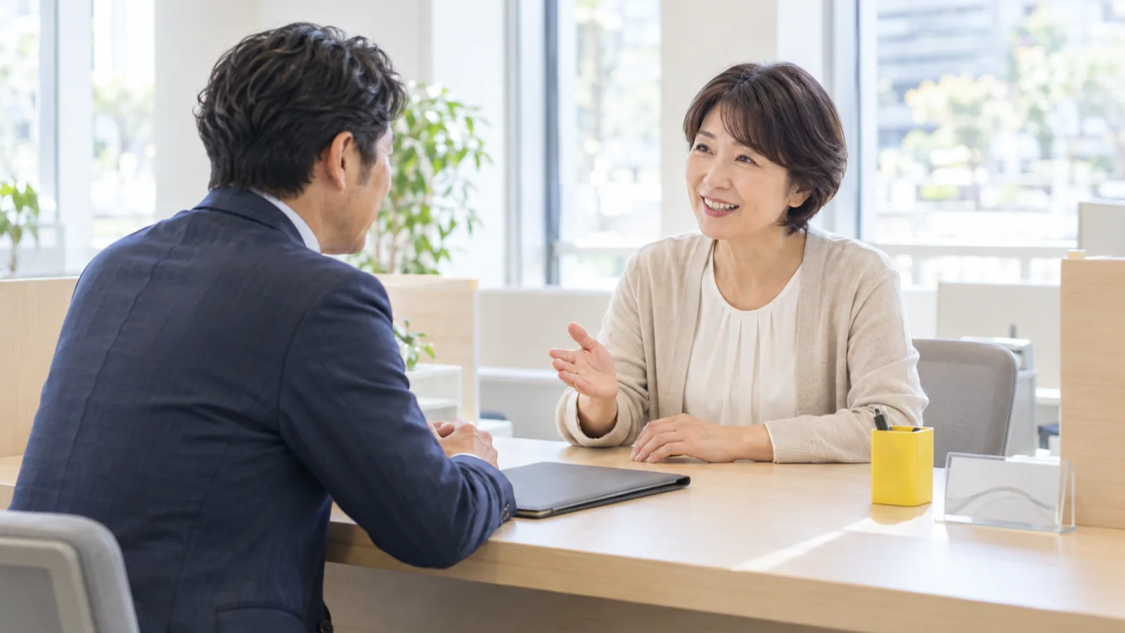 商工会議所の窓口カウンター越しに、相談者と向き合って話す職員