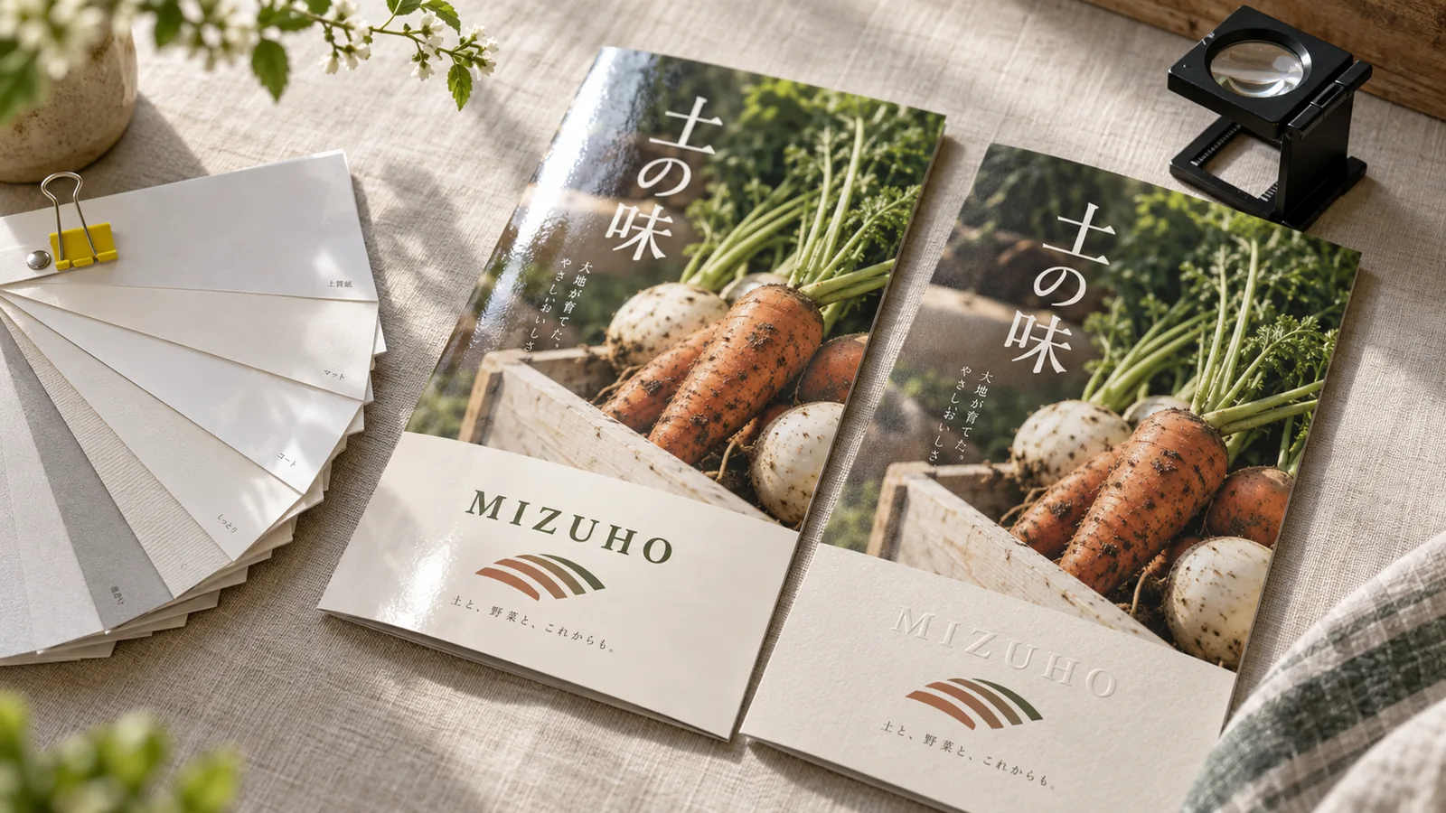 厚さと手触りの違う用紙見本と、同じパンフレットの表紙をつやのある紙とざらっとした紙に刷り分けて並べた接写