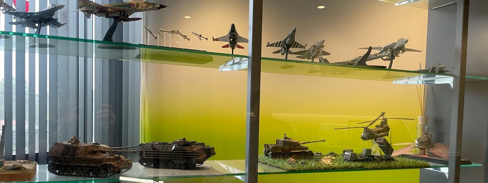 ガラスの棚に並ぶ戦闘機・戦車・ヘリコプターの模型