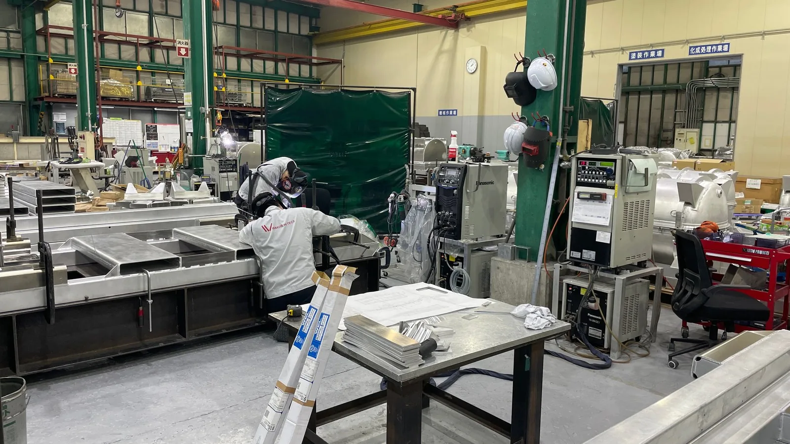 溶接の作業をしている社員さんと、溶接機が並ぶ作業場